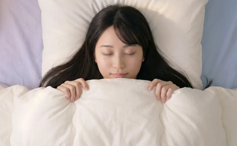 布団に入ってリラックスしている女性の画像