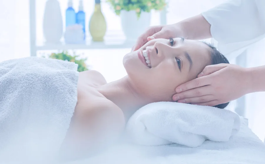 ベッドに横たわり、フェイシャルエステを受けている若い女性の画像