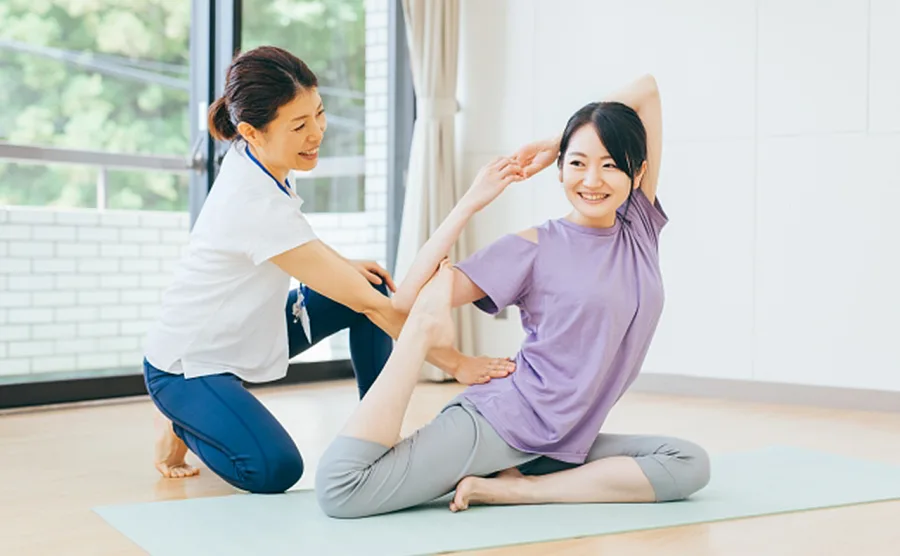 パーソナルトレーナーにヨガを習っている女性の画像