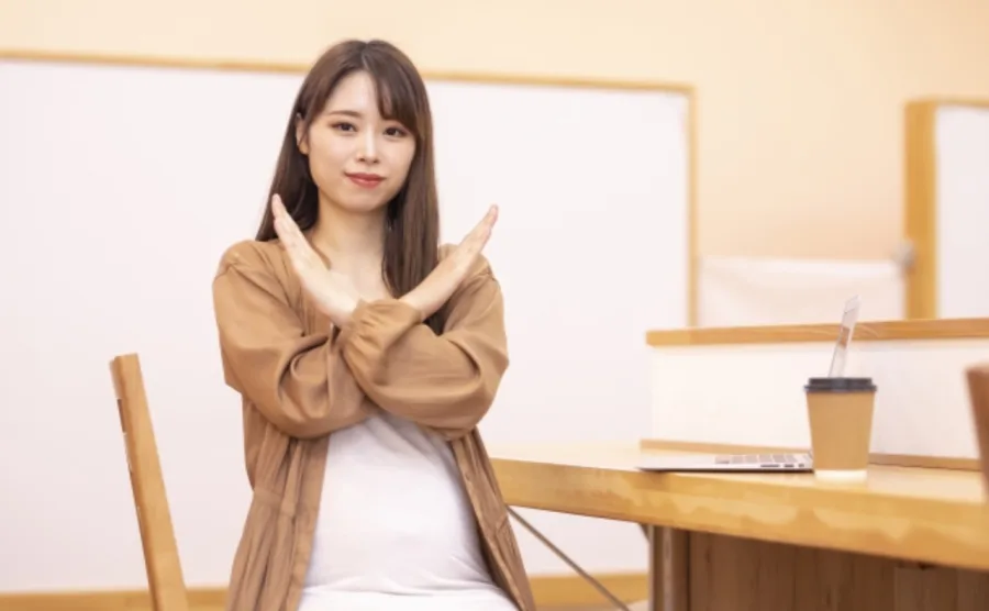 腕をクロスさせてバツマークしている妊婦さんの画像