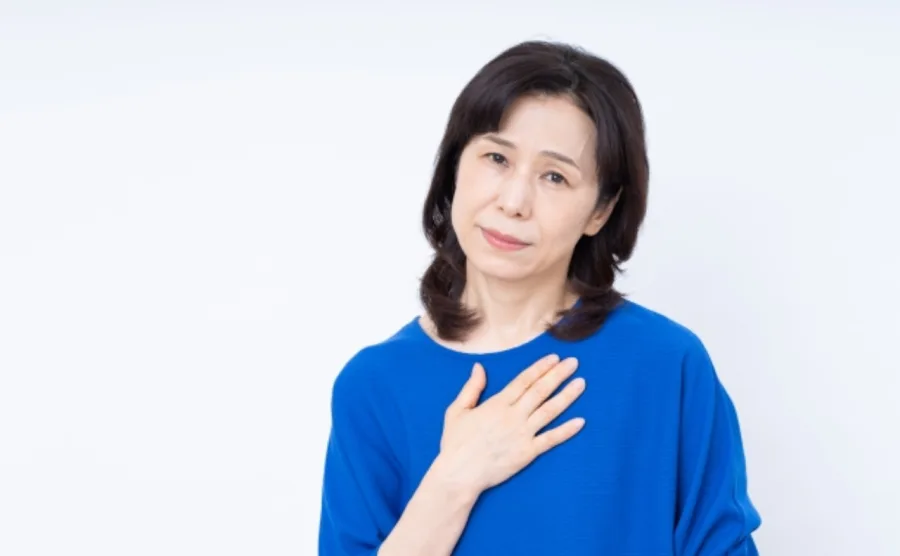 胸を押さえて更年期の症状に悩む50代女性の画像