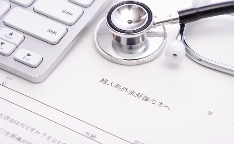 婦人系疾患に関する注意事項と書いてある書類とキーボード・聴診器が写っている診察室内のイメージ画像
