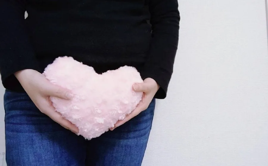女性がハートのクッションを持って下半身を覆っている尿もれのイメージ画像