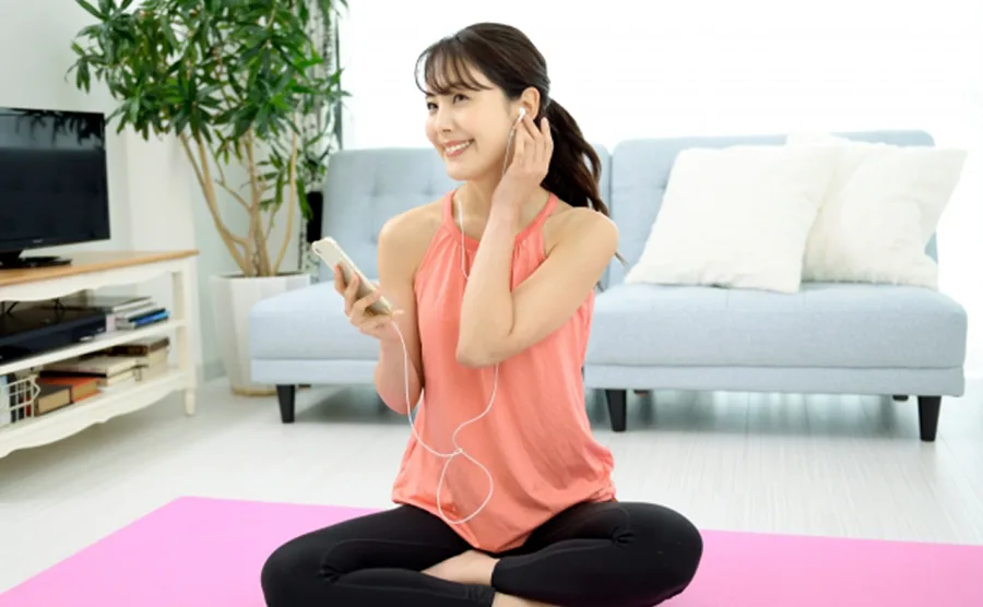 トレーニングウェアを着てスマホで音楽を聴いている女性の画像