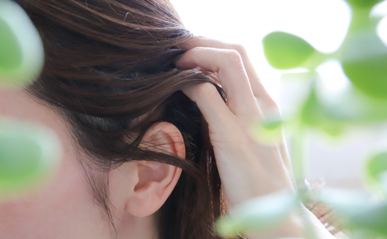 若い女性が髪を耳の後ろにかける仕草の耳元をアップにした画像