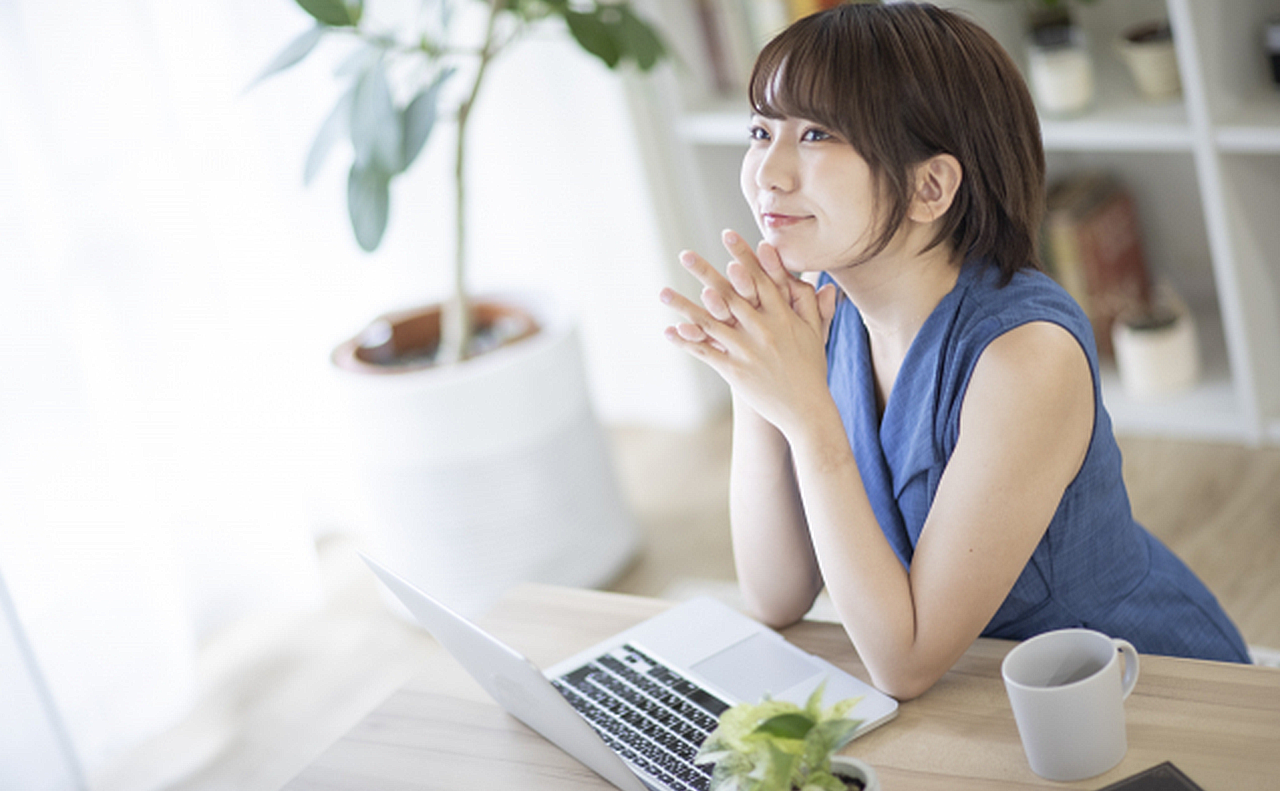 笑顔でパソコンでサロンを検索している女性の画像