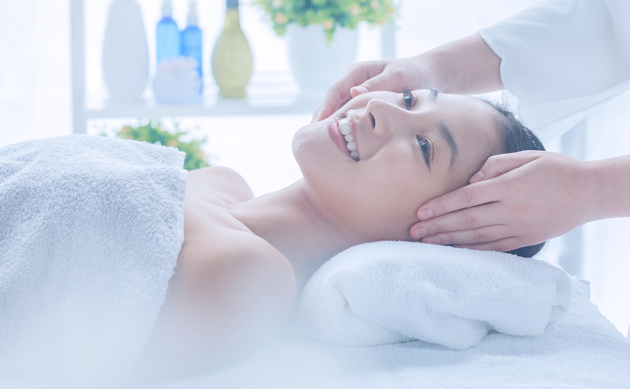 ベッドに横たわり、フェイシャルエステを受けている若い女性の画像