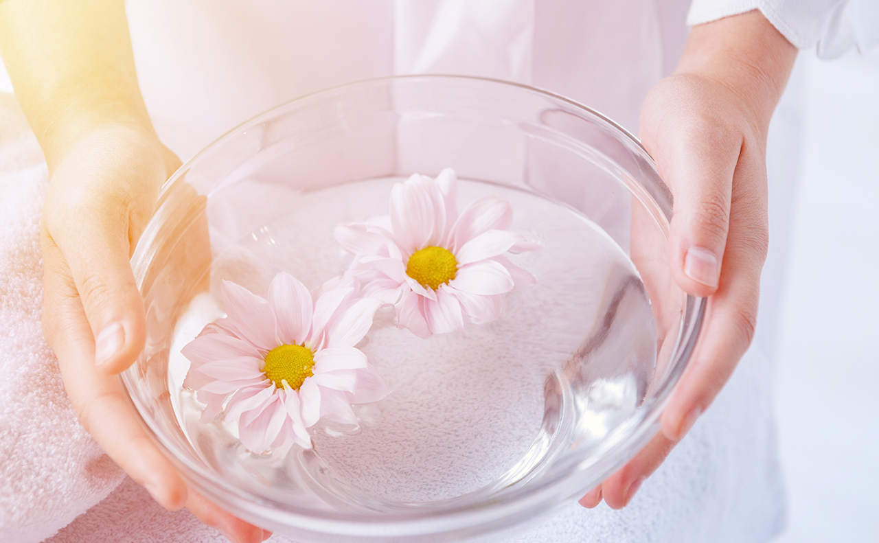 透明のガラスボールにはられた水の上に2つ花が浮いている癒しサロンをイメージさせる画像