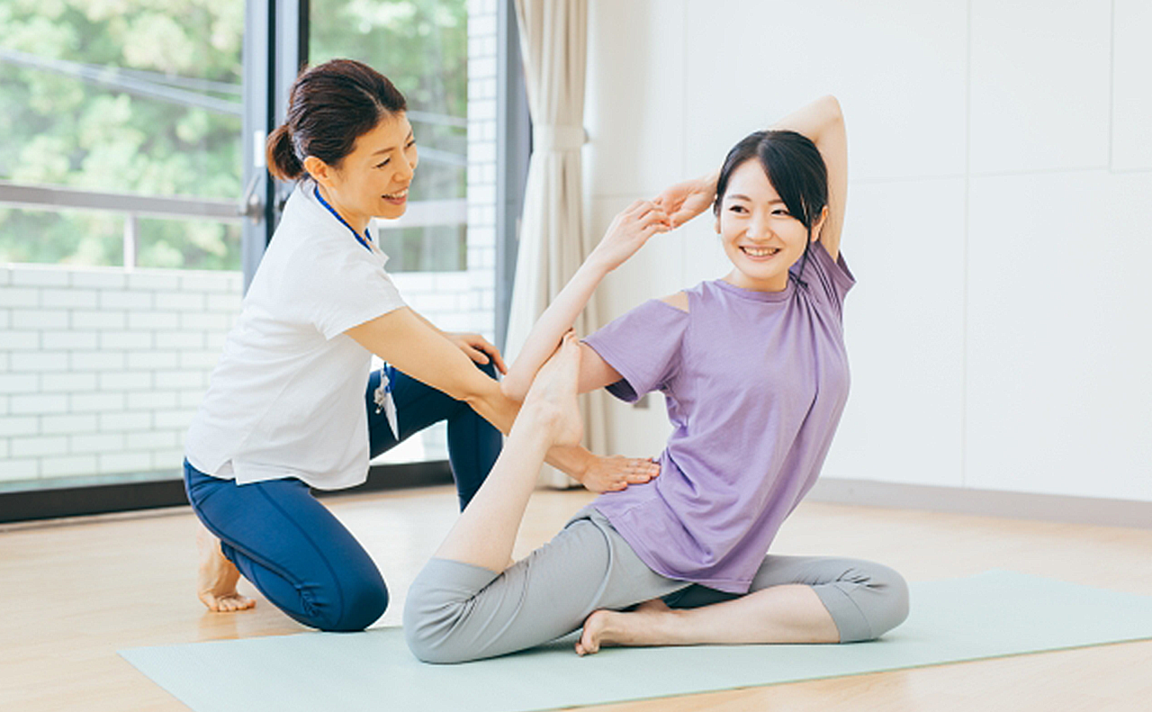 パーソナルトレーナーにヨガを習っている女性の画像