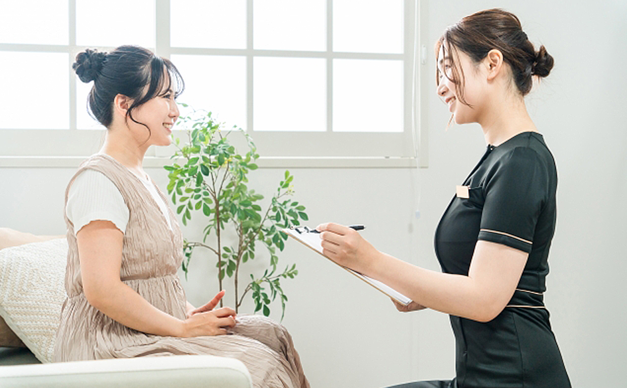 清潔感のある自宅サロンで女性オーナーからカウンセリングを受けている女性の画像